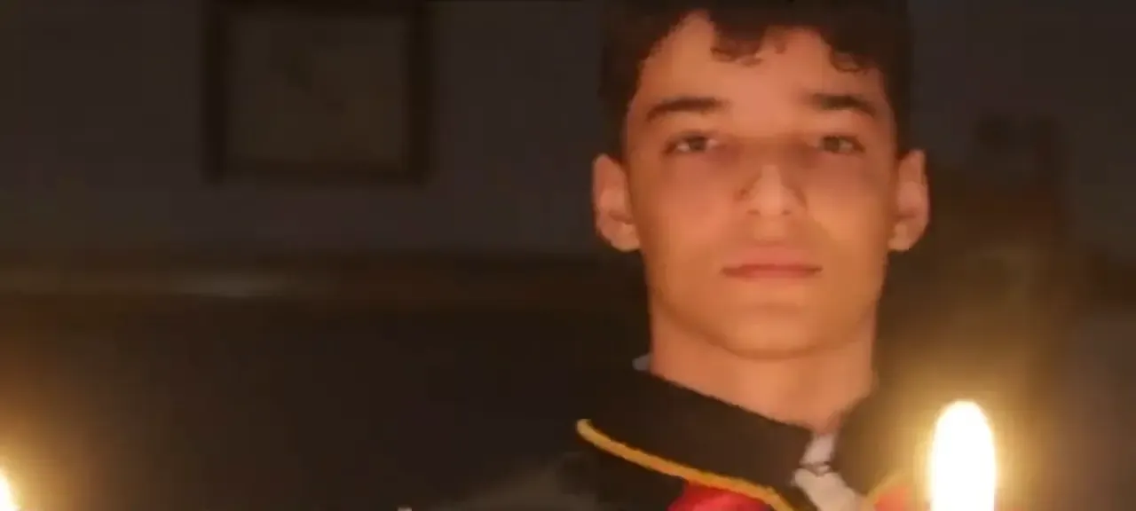 Jovem DeMolay de capa cerimonial entre velas acesas, durante cerimônia do Capítulo