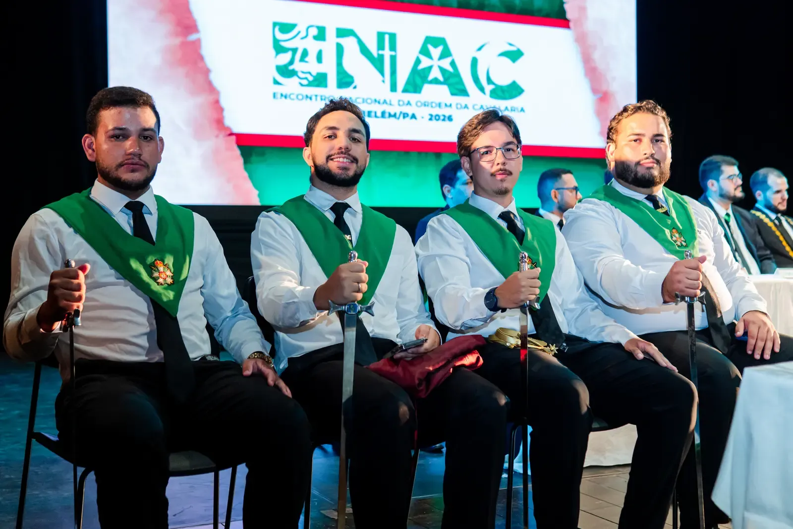 Cavaleiros com faixas verdes sentados lado a lado durante cerimônia do ENAC
